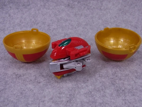 Two gold capsule halves beside the folded red Sword Slasher toy.